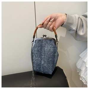 Detailed view of polka dot denim handbag featuring vintage metal kiss-lock and chain strap