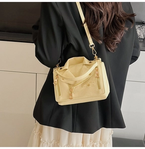 Detail of cream yellow motorcycle jacket style crossbody bag with silver zippers