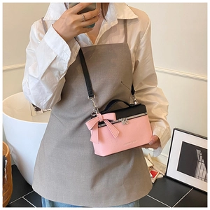 Detail of pink and black crossbody box bag with bow decoration and leather handle