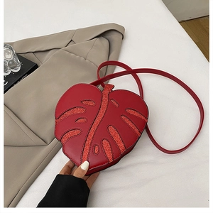 Close-up of red leaf-shaped shoulder bag with shiny sequins and smooth faux leather texture