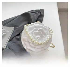 Detailed view of white rose acrylic handbag with pearl handle and golden chain strap