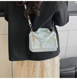Detail of light blue motorcycle jacket style crossbody bag with studs and zippers on a model
