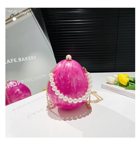 Dettaglio borsa da sera in acrilico rosa a forma di uovo con manico di perle e catena d'oro