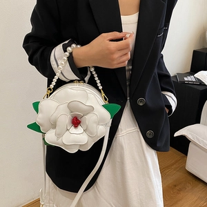 White camellia flower bag with pearl handle and green leaf details worn by a model