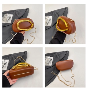 Macro view of dark brown hardshell clutch bag with chunky gold metal handle and chain