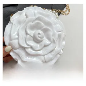 Macro detail of white acrylic rose handbag with gold chain and pearl strap decor