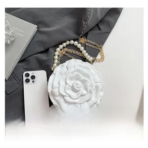 Macro view of white floral evening bag with pearl handle and golden chain details