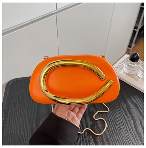 Detail of semi-circular orange acrylic clutch with golden metal handle and chain strap