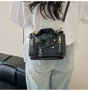 Detail view of black crocodile embossed biker jacket crossbody bag with gold hardware
