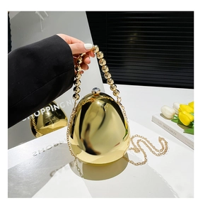 Dettaglio della pochette dorata a forma di uovo con finitura a specchio e manico