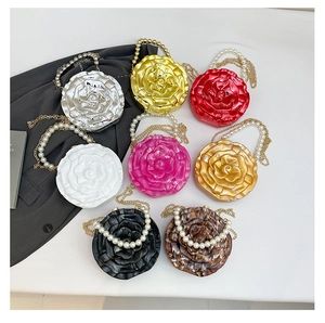 Flat lay of colorful acrylic rose clutch bags with pearl handles and metal chain straps