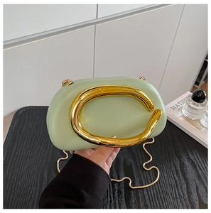 Detailed macro view of mint green clutch bag with gold C-shape metal hardware and chain