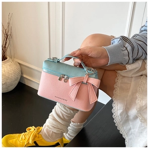 Detail of pink and blue color-block handbag with textured leather and a bow decoration