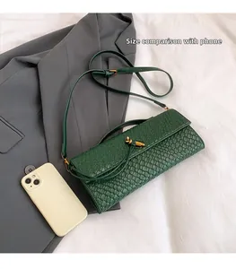 Sac bandoulière vert foncé tressé présenté à côté d'un smartphone pour comparer la taille