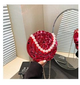 Detailed close-up of a red metallic rose clutch bag with pearl handle and gold chain
