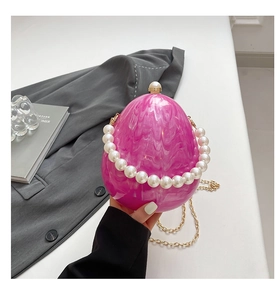 Dettaglio pochette a uovo in acrilico rosa con trama marmo e manico in perle