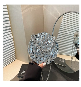 Detailed view of silver metal rose clutch bag with petal texture and beaded chain strap