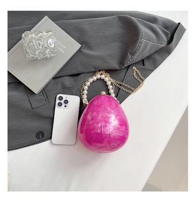 Dettaglio della pochette a uovo in acrilico marmorizzato rosa con manico di perle