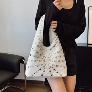 White hobo bag with silver rivets and studs shown on model for a trendy casual look