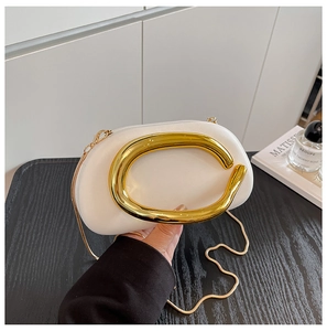 Close-up of white leather handbag with oversized gold C-handle and golden snake chain