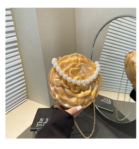 Detailed shot of golden camellia flower acrylic evening bag with pearl handle and chain strap