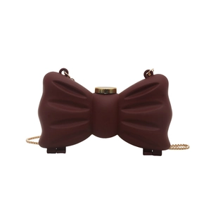 Sac bandoulière chic bordeaux en forme de nœud avec chaîne dorée sur fond blanc