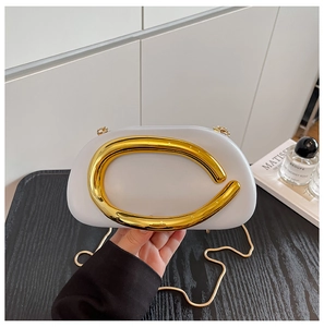 Macro detail of white acrylic clutch bag featuring a prominent gold C-shaped metal handle