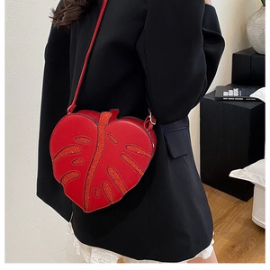 Detail of red leaf-shaped crossbody bag with glitter texture and leather strap
