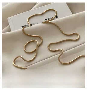 Close-up of elegant gold snake chain necklace on textured fabric and white book