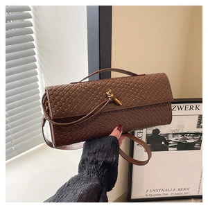 Détail d'un sac bandoulière en cuir tressé marron avec un fermoir nœud en métal doré