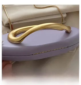 Close-up of purple clutch bag featuring a sleek gold metal handle and chain strap