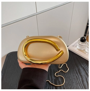 Detailed view of champagne gold evening bag featuring a metallic C-shaped handle and chain