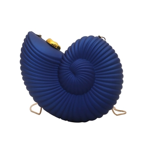Close-up of deep blue conch shell evening clutch with gold chain and spiral texture