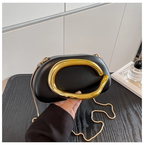 Detail of black matte acrylic box bag featuring a unique oversized gold C-handle and chain
