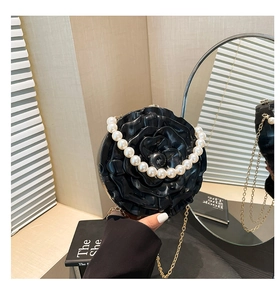 Detailed close-up of a black acrylic 3D rose evening bag with elegant pearl strap handle