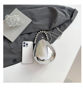 Dettaglio pochette in acrilico argento a forma di uovo con manico e tracolla a catena