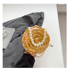 Macro shot of yellow marble acrylic rose clutch with pearl handle and metal chain detail