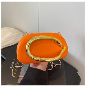 Close-up of bright orange acrylic party clutch with golden C-shaped handle and snake chain