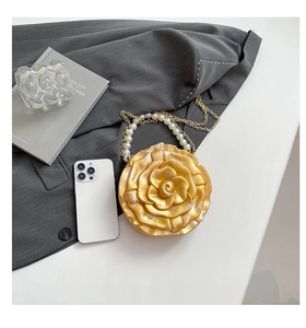 Detail of yellow flower acrylic clutch bag with pearl handle and metal chain strap