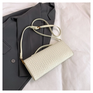 Détail de la texture tressée beige et boucle dorée d'un sac bandoulière élégant