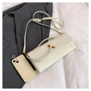 Détail d'un sac bandoulière blanc tressé avec un fermoir en métal doré en forme de nœud