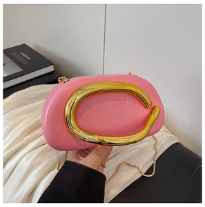 Detailed close-up of pink clutch bag featuring large gold C-shaped metal handle and chain