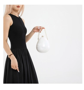 Dettaglio di una pochette ovale in acrilico con manico di perle su un abito nero