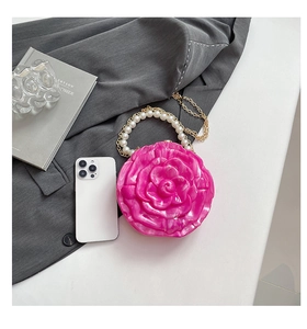Macro view of rose-shaped acrylic evening bag with pearl handle and gold chain