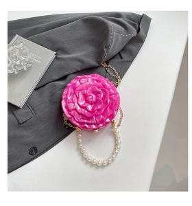Detail of rose-shaped pink acrylic evening clutch with gold chain and pearl handle