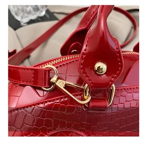 Detail of premium gold metal hooks and red crocodile-textured faux leather handbag