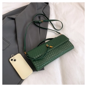 Détail du sac bandoulière tressé vert forêt avec fermoir doré et smartphone pour échelle