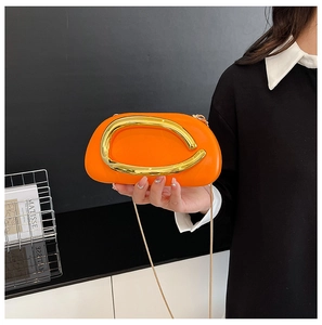 Close-up of vibrant orange crossbody bag featuring a large golden C-shaped metal buckle