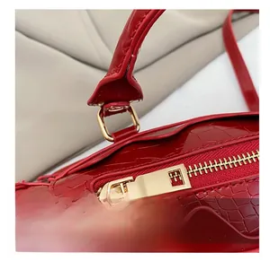 Detailed close-up of smooth gold zipper and crocodile pattern on red patent leather bag