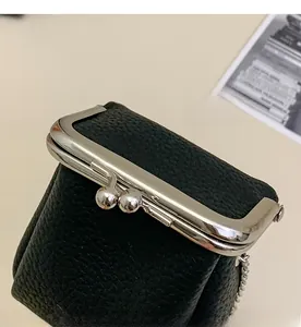 Detail of silver metal clasp on black lychee grain leather mini lipstick crossbody bag